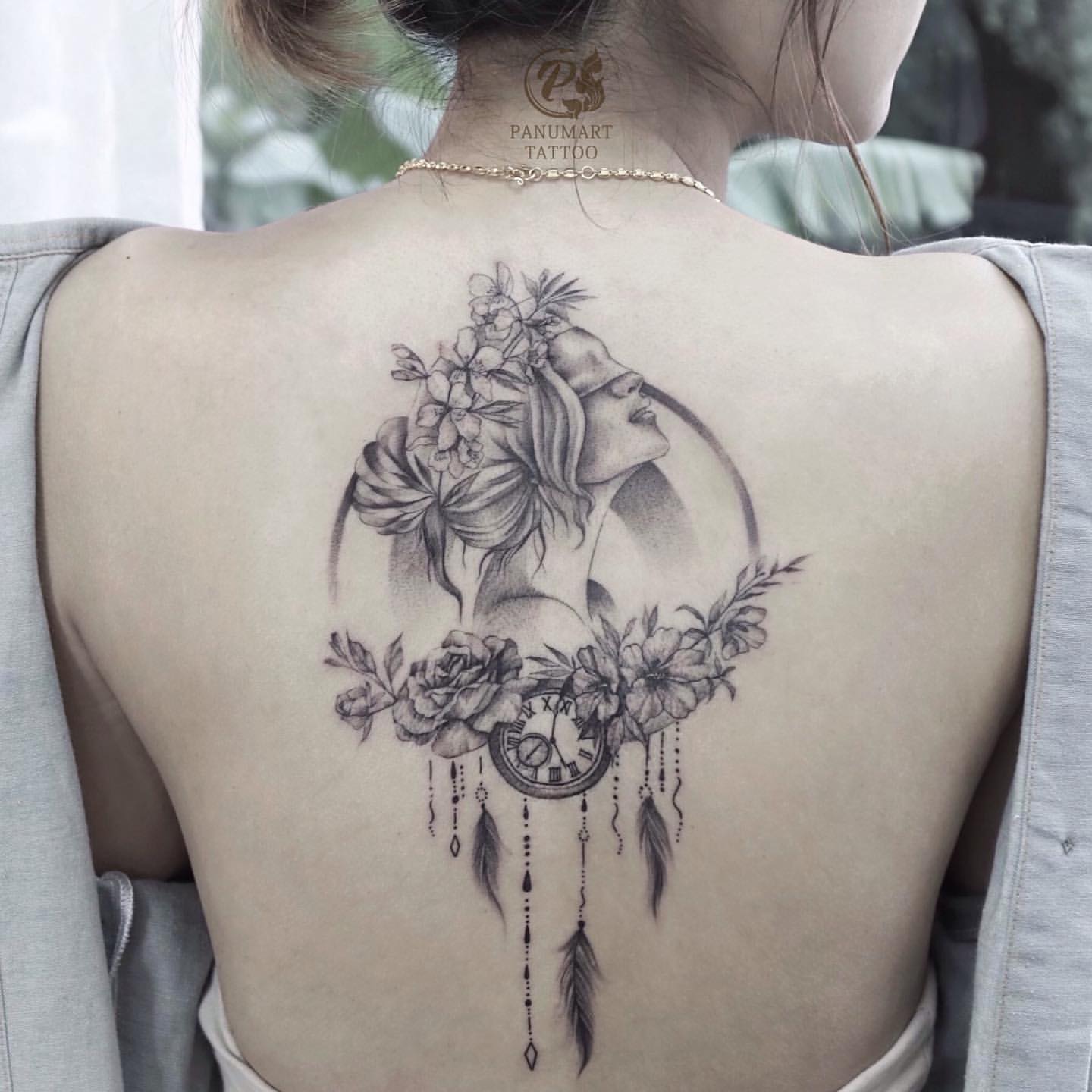 Ethereal femininity meets celestial symbolism in this breathtaking back piece, where a graceful woman's silhouette emerges from a crescent moon adorned with delicate blooms. The intricate dreamcatcher elements below create beautiful movement with dangling feathers and beads, while the fine-line shading technique gives the entire design an almost pencil-sketch quality. Perfect placement on the spine transforms the back into a canvas for this mystical tribute to lunar energy and feminine power ✨