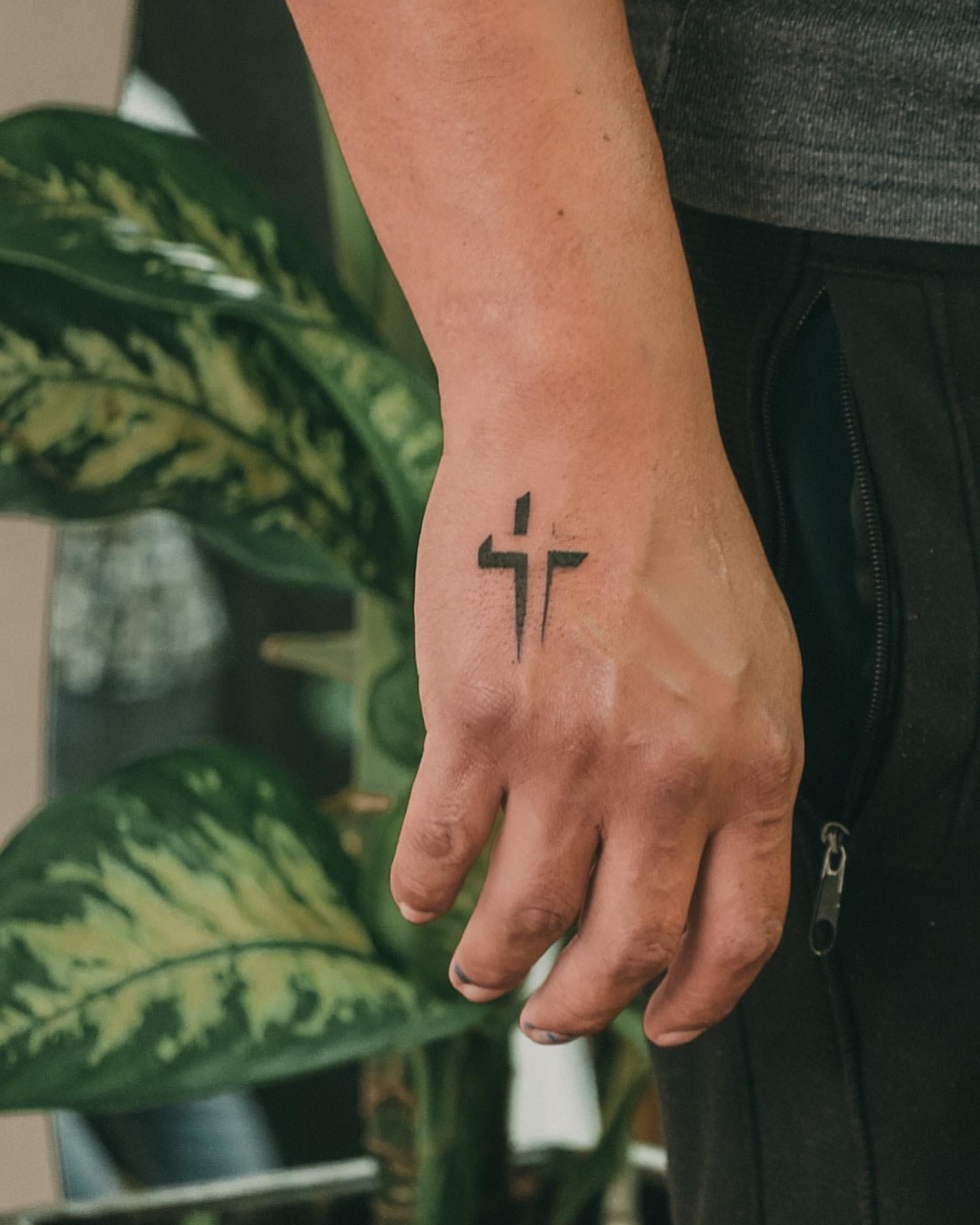 Bold brushstroke artistry transforms a classic Christian symbol into something beautifully modern on this hand placement. The cross appears painted with confident, sweeping strokes that give it an almost calligraphy-inspired elegance against the skin ✝️ Perfect positioning between thumb and forefinger makes this a subtle yet meaningful statement piece.