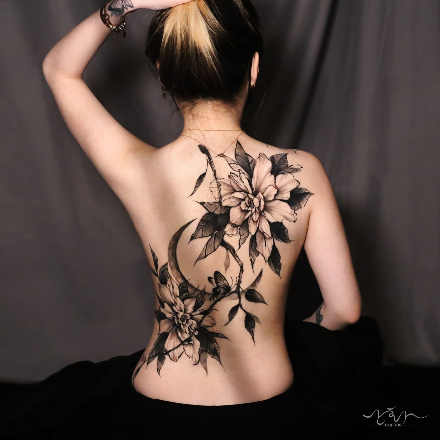 Delicate dahlia blooms cascade down this stunning back piece, creating an enchanting botanical garden across the spine. The masterful black and gray shading brings incredible depth to each petal, while the organic flow from shoulder blade to lower back creates a naturally elegant silhouette that moves beautifully with the body's curves. 🌸