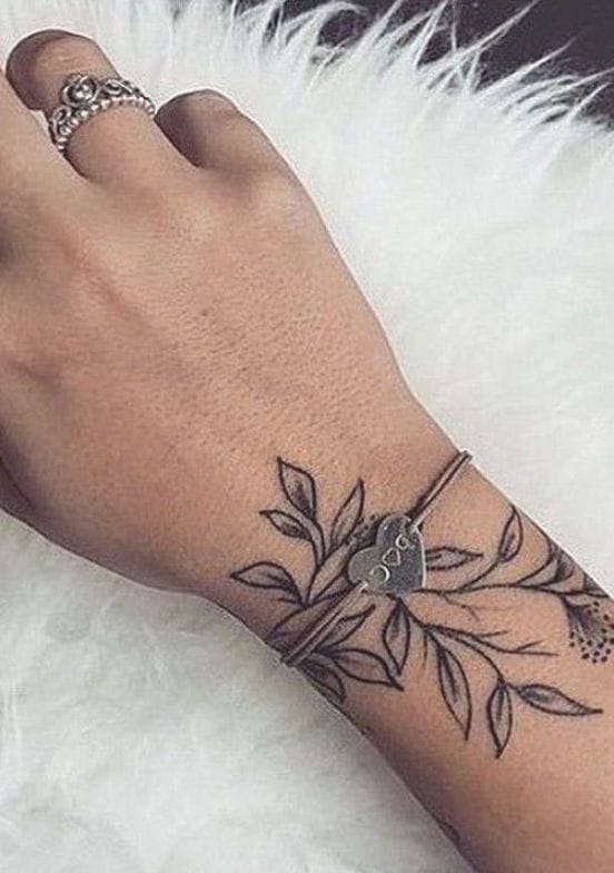 Delicate botanical linework cascades gracefully around this wrist like nature's own jewelry, creating an organic bracelet that moves with every gesture. The flowing leaves and intricate details demonstrate how minimalist black ink can create maximum visual impact when expertly placed on such a visible canvas. 🌿