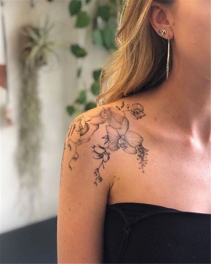 Delicate orchids cascade down this shoulder like nature's own jewelry, their petals rendered in soft grayscale that catches the light beautifully. The botanical design flows seamlessly from shoulder to upper arm, creating an elegant silhouette that's both feminine and striking 🌺