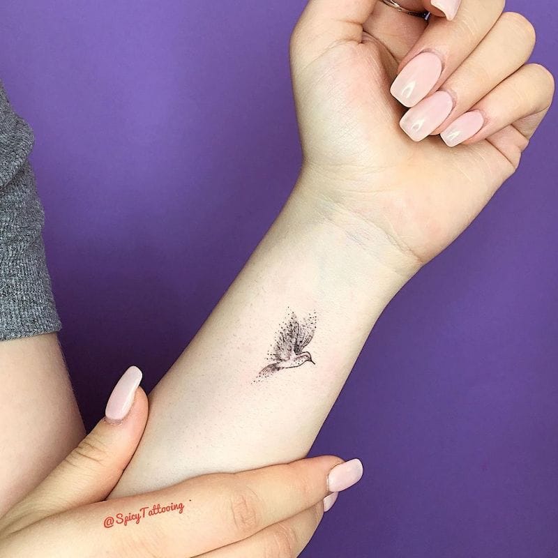 Delicate dotwork creates ethereal magic in this minimalist bird design, where tiny stippled details form wispy feathers that seem to flutter right off the skin. The strategic wrist placement transforms an everyday gesture into an artistic moment, while the subtle shading technique gives this fine-line piece incredible depth and movement. ✨