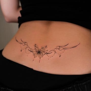 Delicate linework blooms across the lower back in this stunning botanical piece, where flowing vines and scattered petals create an organic garden that moves with the body's natural curves. The fine-line technique gives it an almost ethereal quality, like pressed flowers preserved in ink 🌸