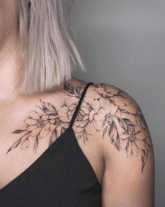 Delicate peonies cascade across the shoulder in this breathtaking black and gray masterpiece, creating an elegant floral embrace that flows naturally with the body's curves. The intricate linework and soft shading technique brings each bloom to life, while the strategic placement allows the design to peek beautifully from clothing 🌸 A perfect example of how botanical tattoos can be both feminine and bold.