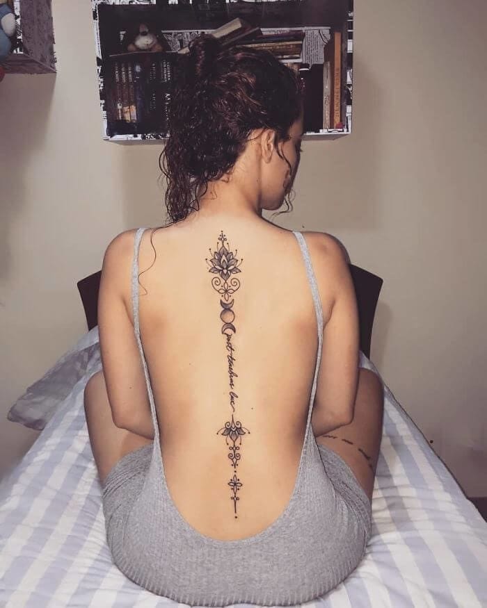 A breathtaking vertical masterpiece flows down the spine like an elegant botanical river, featuring ornate mandala elements that cascade into delicate script and intricate geometric details. The impeccable line work creates a stunning contrast against the skin, transforming the back into a canvas of sacred geometry and feminine grace. This spine tattoo perfectly balances bold decorative motifs with refined scripted text for an absolutely mesmerizing effect ✨