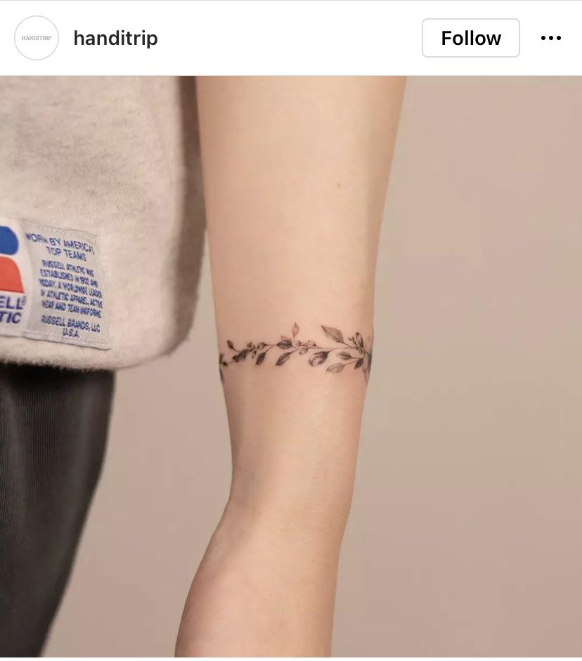 Delicate botanical artistry transforms this wrist into a living canvas, where intricate leaves and tiny berries dance around the arm in perfect harmony. The fine line work creates an almost ethereal quality, as if nature itself has left its gentle mark on the skin 🌿