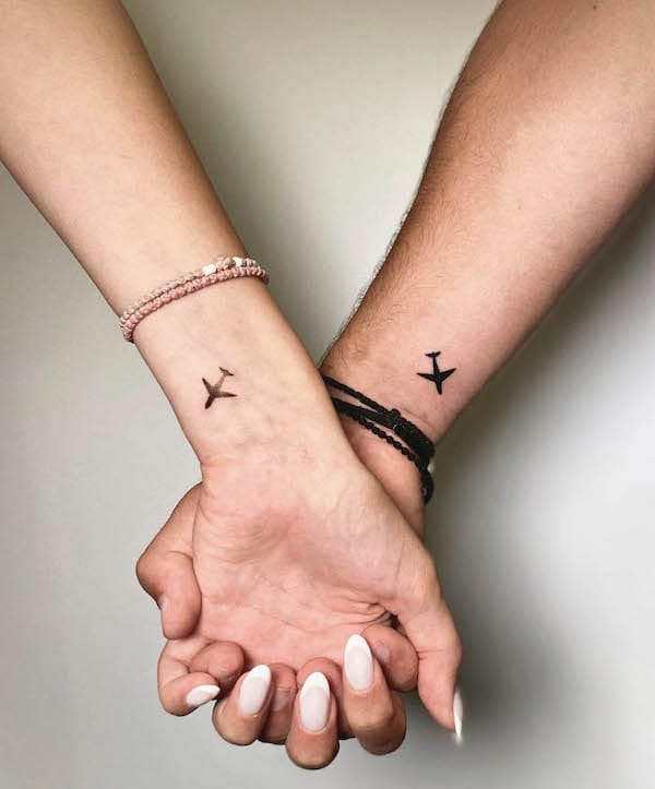 Simple black airplane silhouettes dance across two wrists in perfect harmony, creating an intimate symbol of shared adventures and wanderlust ✈️ The minimalist design speaks volumes about a couple's commitment to exploring the world together, with each delicate aircraft representing dreams that take flight when hearts are united. Positioned beautifully on the inner wrists, these matching tattoos serve as daily reminders that love knows no boundaries.