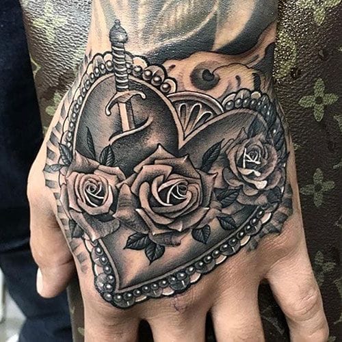 A magnificent heart locket unfolds across this hand tattoo, its ornate Victorian details housing a garden of meticulously shaded roses 🌹 The artist's masterful use of light and shadow creates incredible depth, making the metallic locket appear three-dimensional against the skin. Bold placement on the hand ensures this romantic masterpiece becomes a constant reminder of love's enduring beauty.