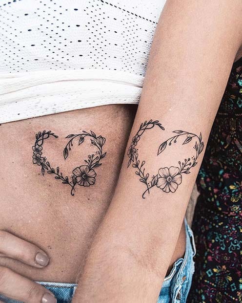Delicate botanical hearts intertwine on two arms, creating a stunning mirror effect that celebrates the beauty of connection 🌿 The fine line work transforms simple flowers and leaves into romantic wreaths, proving that matching tattoos can be both meaningful and artistically refined.