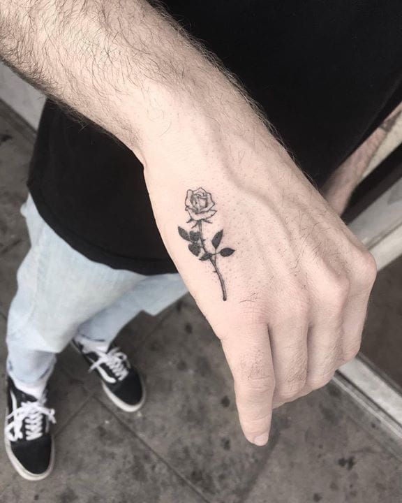 Delicate linework transforms this hand into a canvas for botanical beauty, with a single rose stem gracefully following the natural contours from wrist to knuckle. The minimalist black ink design creates an elegant contrast against pale skin, making every gesture a subtle display of floral artistry 🌹
