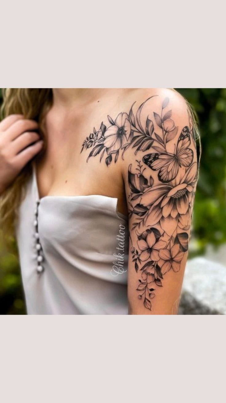 Cascading from shoulder to elbow, this breathtaking black and grey floral sleeve transforms the entire arm into a botanical garden in bloom. The masterful shading technique brings incredible depth to each hibiscus and butterfly, while delicate leaves and smaller blossoms create a natural flow that follows the arm's contours beautifully 🌺