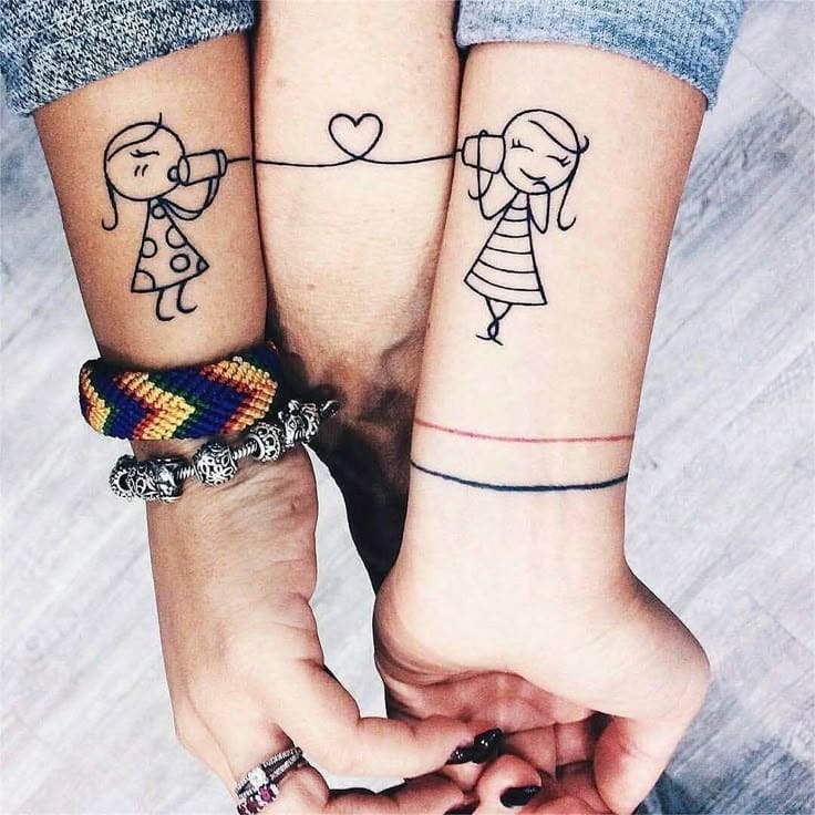 Two arms become a canvas for connection in this adorable couple's tattoo featuring stick figure girls chatting through tin can telephones, with a heart floating between them on the middle arm. The whimsical line art style captures that nostalgic childhood friendship vibe, while the coordinated wrist bands add an extra touch of matching symbolism 💕 Perfect for best friends or partners who want to celebrate their unbreakable bond!