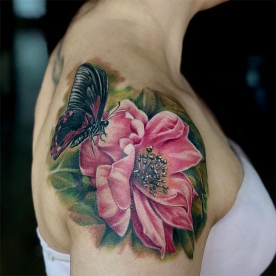 Nature's delicate dance comes alive in this stunning shoulder piece, where a vibrant butterfly hovers gracefully above a blooming pink flower. The realistic shading and botanical details create an almost three-dimensional effect that seems to flutter with every movement. A perfect symbol of transformation and natural beauty captured in permanent ink 🌸