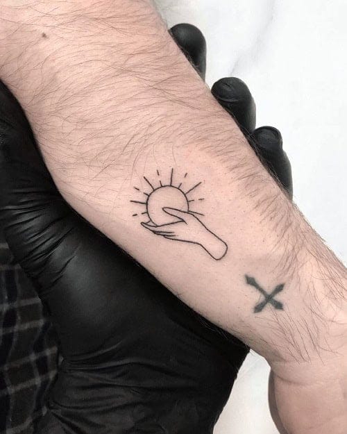 A minimalist sun and wave design flows gracefully across the wrist, creating a perfect harmony between celestial and oceanic elements. The delicate linework captures the essence of sunrise over water, while a small cross below adds personal meaning to this beautifully balanced piece ☀️