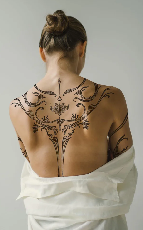 Flowing like ornate architectural details across her back, this Art Nouveau-inspired masterpiece transforms the human form into a living canvas of botanical elegance. The symmetrical design features graceful stems and flourishing fronds that seem to grow organically from her spine, creating an enchanting tree-of-life motif that celebrates both nature and sophisticated artistry. 🌿