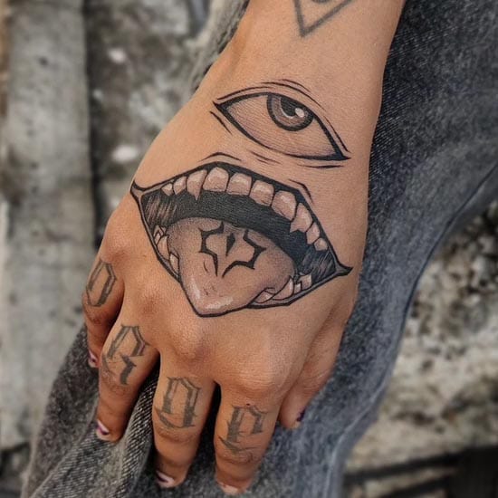 Bold linework transforms this hand into a mesmerizing canvas where an all-seeing eye hovers above a gaping mouth filled with intricate dental details. The strategic placement across the hand creates an optical illusion that brings the design to life with every gesture, while the black ink's precise shading adds dimensional depth to each anatomical element. 👁️ Perfect execution of surreal body art that blurs the line between skin and storytelling.