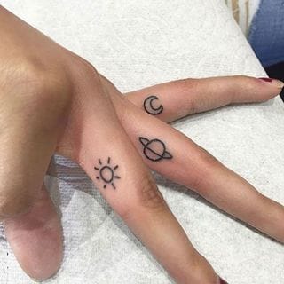 Celestial symbolism takes on intimate meaning with this delicate finger tattoo duo featuring a radiant sun and crescent moon. The minimalist line work creates a beautiful contrast against skin tone, while the placement on adjacent fingers allows the wearer to bring these cosmic forces together with a simple gesture ☽☀️