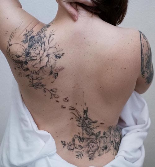 Delicate botanical artistry cascades down this person's spine in an enchanting display of fine-line florals and flowing elements. The ethereal design seamlessly weaves from shoulder blade to lower back, creating a stunning vertical composition that celebrates the natural curves of the body while showcasing masterful black and gray shading techniques. 🌿