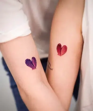 Delicate watercolor hearts bloom on paired forearms, creating an intimate symbol of connection between two people. The artistic brushstroke technique gives these matching tattoos a soft, painted quality that feels both romantic and contemporary 💕 Perfect placement for couples who want their love story written in ink where they can always see it.