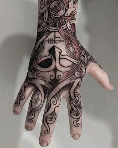 Ancient Norse mysticism flows across this hand in mesmerizing detail, where intricate knotwork dances around what appears to be a stylized raven or mythological creature at the center. The bold black linework creates stunning contrast against skin, with Celtic-inspired patterns weaving seamlessly from wrist to fingertips in a design that's both spiritually meaningful and visually striking. ⚔️